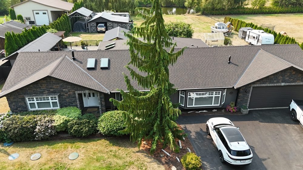 Finished asphalt shingle roof on a large rancher with stone accents, drone view